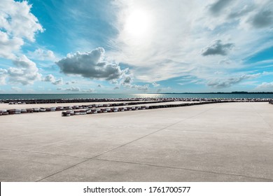 Wide Cement Road And Lake Under Blue Sky.