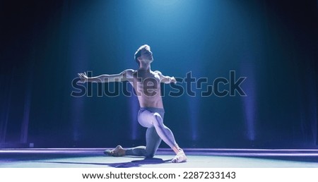 Wide Cinematic Shot of Athletic Man Dancing and Rehearsing on Classic Theatre Stage with Dramatic Lighting. Graceful Classical Ballet Male Dancer Performing his Choreography Professionally