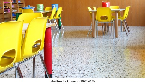 Wide Classroom Of A Nursery School With Tables And Chairs And Drawings Of Children