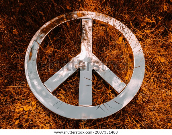 Wide close shot of Peace\
Sign for nuclear disarmament set against a fiery orange grass\
background 