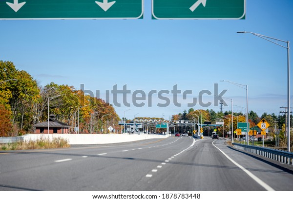 Wide divided turnpike\
highway with toll station with multi-line payment terminal for fast\
payment and working without transportation traffic delay in Maine\
New England