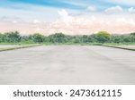 Wide empty asphalt parking lot background with white painted lines marked lens. Outdoor empty space parking lot with trees and cloudy sky. outside parking lot in a park
