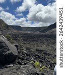 A wide, empty view from the floor of the Kīlauea Iki Crater reveals hardened lava textures, steam vents, and steep crater walls under open sky in Hawaiʻi Volcanoes National Park.