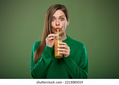 Wide Eyed Woman Advertising Portrait On Green With Orange Juice Bottle. Drinking With Straw.