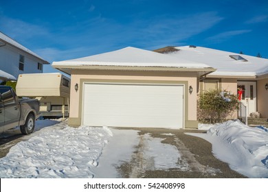 Wide Garage Of Big Luxury House With Parked Car And RV Trailer Beside. Driveway And Entrance Of Residential House On Winter Sunny Day