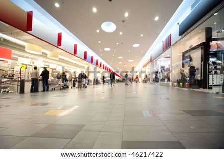 Wide hall and buyers in trading center with shops on both sides