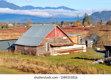 Wide, high angle view of a rustic barn  set in a valley surrounded by mountains. 