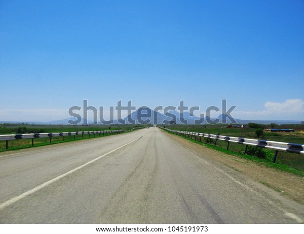 Wide\
highway and mountain. Clouds over and blue\
sky