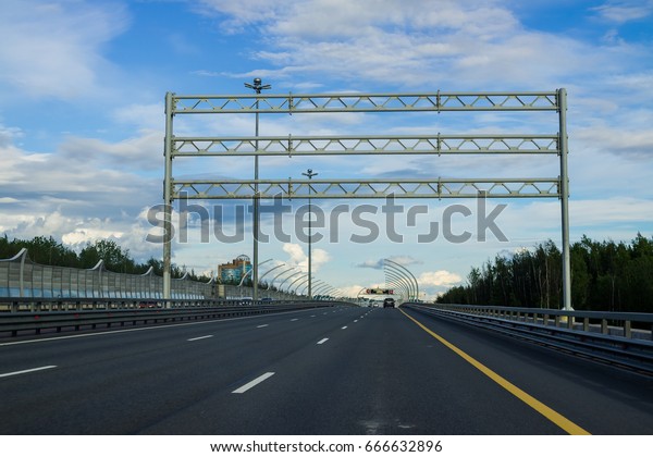 Wide highway with road signs and information\
banner over traffic lanes. Highway ring road around the big\
city.High Speed Diameter\
overpass