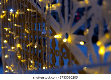 A wide horizontal shot frames decorative lights strung along a stylized fence, using strong leading lines against a muted blue backdrop with warm orange light accents.