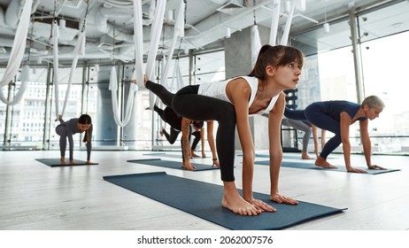 Wide image of sporty millennial ethnic girl in sportswear practice fly yoga with multiethnic diverse group. Active toned young woman do sports have stretching workout training on hammock. - Powered by Shutterstock