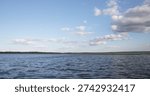 Wide lake landscape with dramatic clouds over water and distant forest shoreline