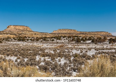 Wide Open Desert Vista Covered In Snow With Rocky Mesa Plateau Mountains On Clear Day In Rural New Mexico