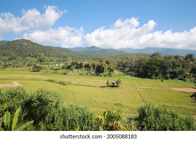 A Wide Open Field With Mountains And Blue Sky Background