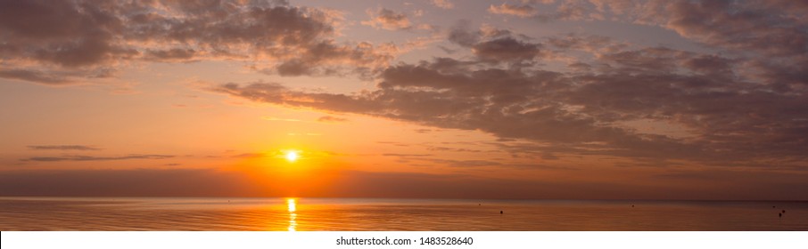 Wide panorama of beautiful sunset over calm sea. 