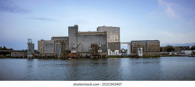 Wide panorama of old industrial processing factory and silo building on the shore of the Maas river in the Dutch harbour infrastructure port city of Rotterdam
