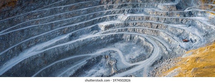Wide panorama of open pit stone quarry with stepped wall, excavator and stone crusher machines