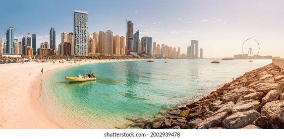 Wide panorama of the Persian Gulf with sandy beach and Bluewaters Island with the worlds famous largest Ferris wheel Dubai Eye and numerous skyscrapers with hotels and residences