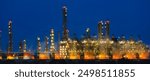 Wide Panoramic horizonal photography of night oil and gas refinery petroleum petrochemical industry plant building light blue night sky.