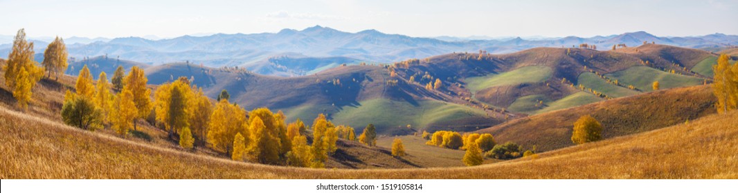 Wide panoramic view, autumn. The picturesque valley. Forested slopes and mountains in the distance in a blue haze.