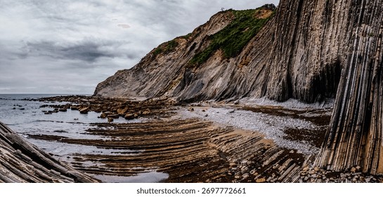 Wide Panoramic View of the Dramatic Layered Flysch Cliffs and Rock Formations at Low Tide on Itzurun Beach in Zumaia, Basque Country, Spain