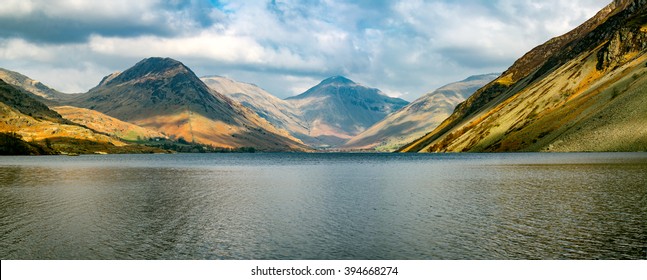 Wide panoramic view of mountains and lake on a cloudy day at Wast Water in the Lake District, UK.
