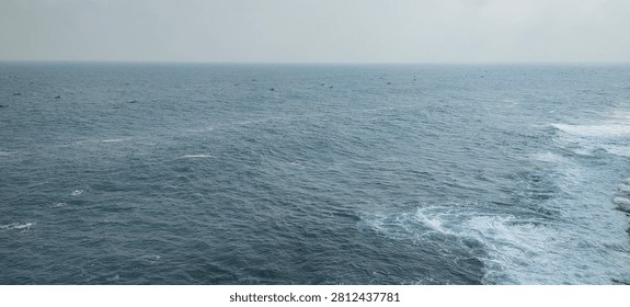 Wide panoramic view the open ocean with gentle waves and a distant horizon under a clear daytime sky. Peaceful seascape showcasing the beauty of tropical waters and a tranquil coastal environment in Indonesia.
