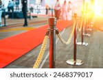 Wide panoramic view rope fencing with gold pillars with a red carpet for celebrities and guests of an expensive event with crowds of people