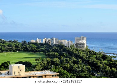 Wide panoramic view showcasing the dense buildings of the modern Honolulu cityscape against the deep blue of the vast Pacific Ocean in Hawaii.