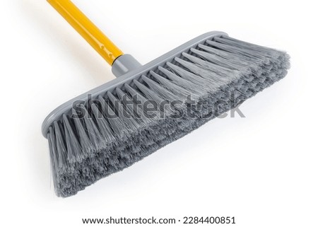 Wide plastic brush of the sweeping broom with gray synthetic bristles, close-up on a white background

