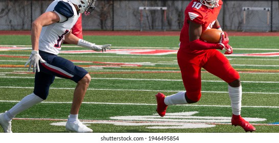 Wide Receiver Running Away From Defender Who Is Trying To Tackle Him During A High School Football Game.