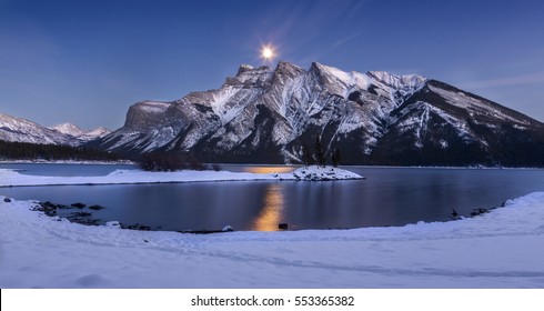 Wide Rocky Mountains Panoramic Winter Landscape with Full Moon Rising over Lake Minnewanka Water in Banff National Park Alberta Canada