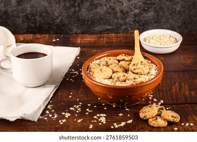 Wide rustic breakfast setup with coffee cup, oat flakes bowl topped with chocolate cookies and extra cookies in foreground, ideal copy space composition.