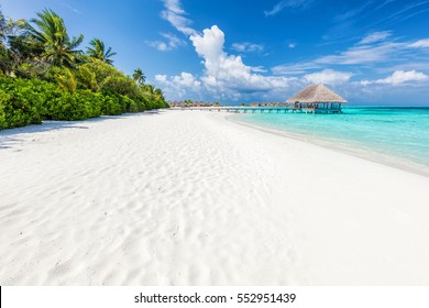 Wide Sandy Beach On A Tropical Island In Maldives. Coconut Palms And Water Lodge On Indian Ocean.