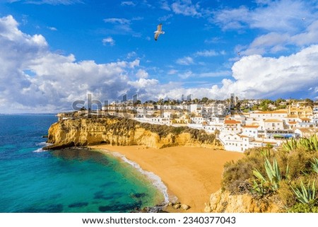 Wide sandy beach, white houses, cloudy sky with seagulls, Carvoeiro, Algarve, Portugal