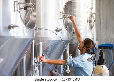 Wide Shot Of A Brewery Worker Checking Fermentation Process In Steel Vat