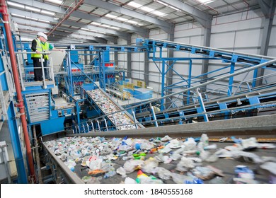 Wide shot of Businessman and worker talking on platform above conveyor belts in recycling plant - Powered by Shutterstock