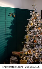 A Wide Shot Of A Christmas Tree Decorated With Golden-orange Shiny Balls And Lights In A Living Room.