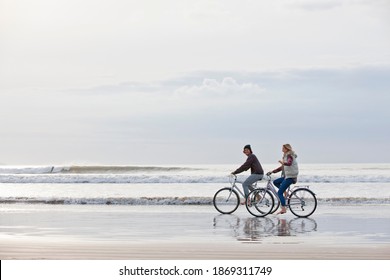 A Wide Shot Of A Couple Riding Bicycles On The Beach