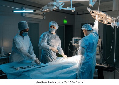 Wide shot of doctor in surgical uniforms and masks adjusting light before operation in dark operating theatre. Surgery, hospital, medical and healthcare services. Concept of surgery and emergency. - Powered by Shutterstock