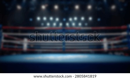 A wide shot of an empty boxing ring with red and blue ropes illuminated by overhead stadium lights in a dark arena.