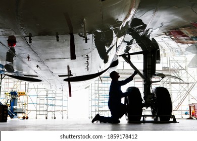 Wide shot of an engineer inspecting the landing gear of a passenger jet at a hangar. - Powered by Shutterstock