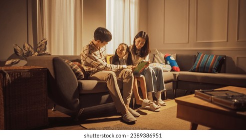 Wide Shot of a Family of Three in the Living Room Using Technology: Korean Parents and Their Little Daughter Playing Games Together on a Digital Tablet Computer, Laughing and Having Fun - Powered by Shutterstock