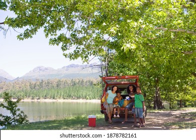 Wide shot of a family in the trunk of a car under a tree on a sunny day near the lake. - Powered by Shutterstock