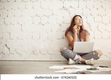 Wide shot of a freelance blog post writer working in a bright studio space sitting in a cafe or a campus surrounded by textile samples and fashion ilustrations