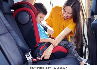 Wide Shot Of Gorgeous Mom Helping Son Sitting In Baby Seat To Fasten Seat Belt