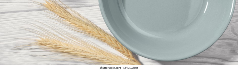 Wide Shot Of Half Empty Plate And Two Wheat Stalk On Wooden Background