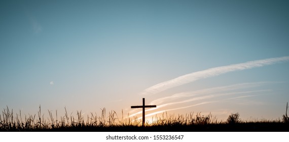 A Wide Shot Of A Hand Made A Wooden Cross In A Grassy Field With A Blue Sky In The Background