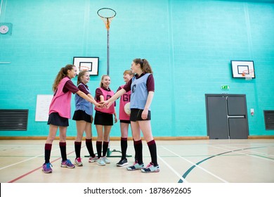 Wide Shot Of High School Girls With A Netball Touching Hands In A Huddle Before A Game.