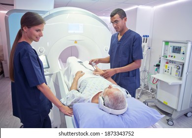 Wide Shot Of Hospital Radiographers With A Male Patient Operating MRI Scanner